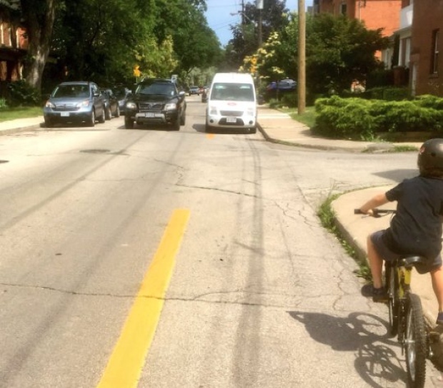 A cyclist is unable to move forward due to a Canada Post delivery truck blocking the bike lane.