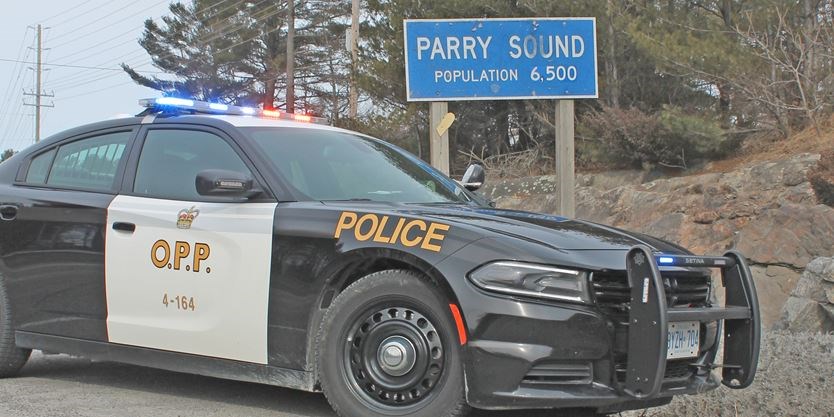 OPP cruiser in front of Parry Sound population sign