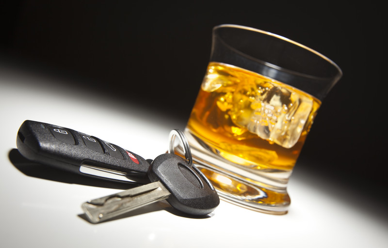 Car keys next to a glass of alcohol