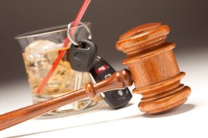 Stock image of a gavel in front of keys hung on the straw of an alcoholic drink