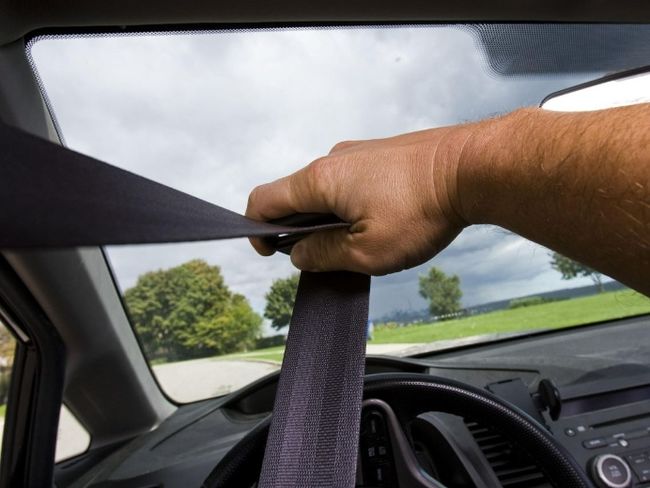 A man pulls his seatbelt in front of the camera