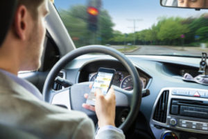 Close-up Of A Person's Hand Sending Text Message By Mobile Phone While Driving Car