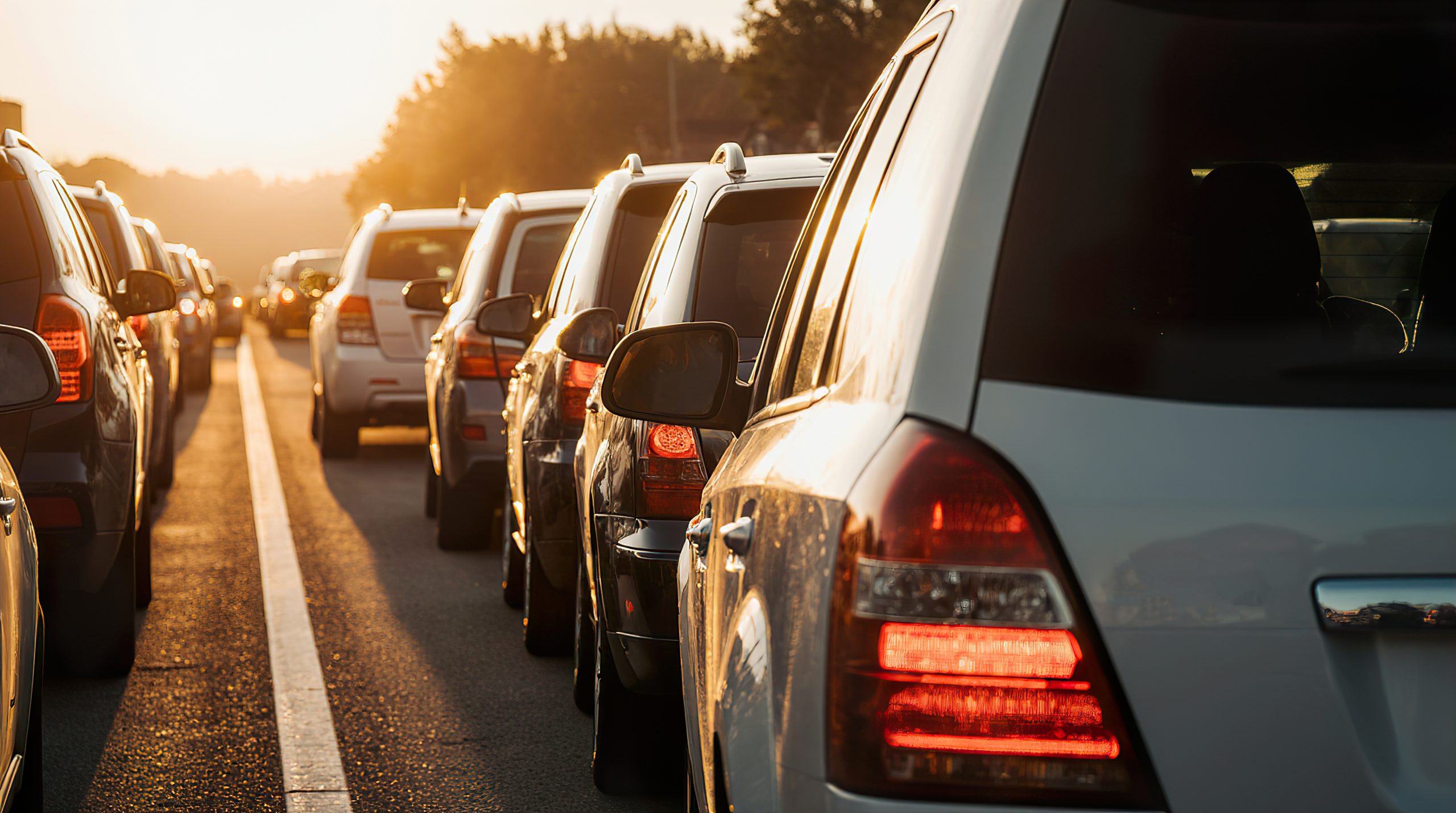 Highway traffic jam with multiple vehicles in line during sunset.