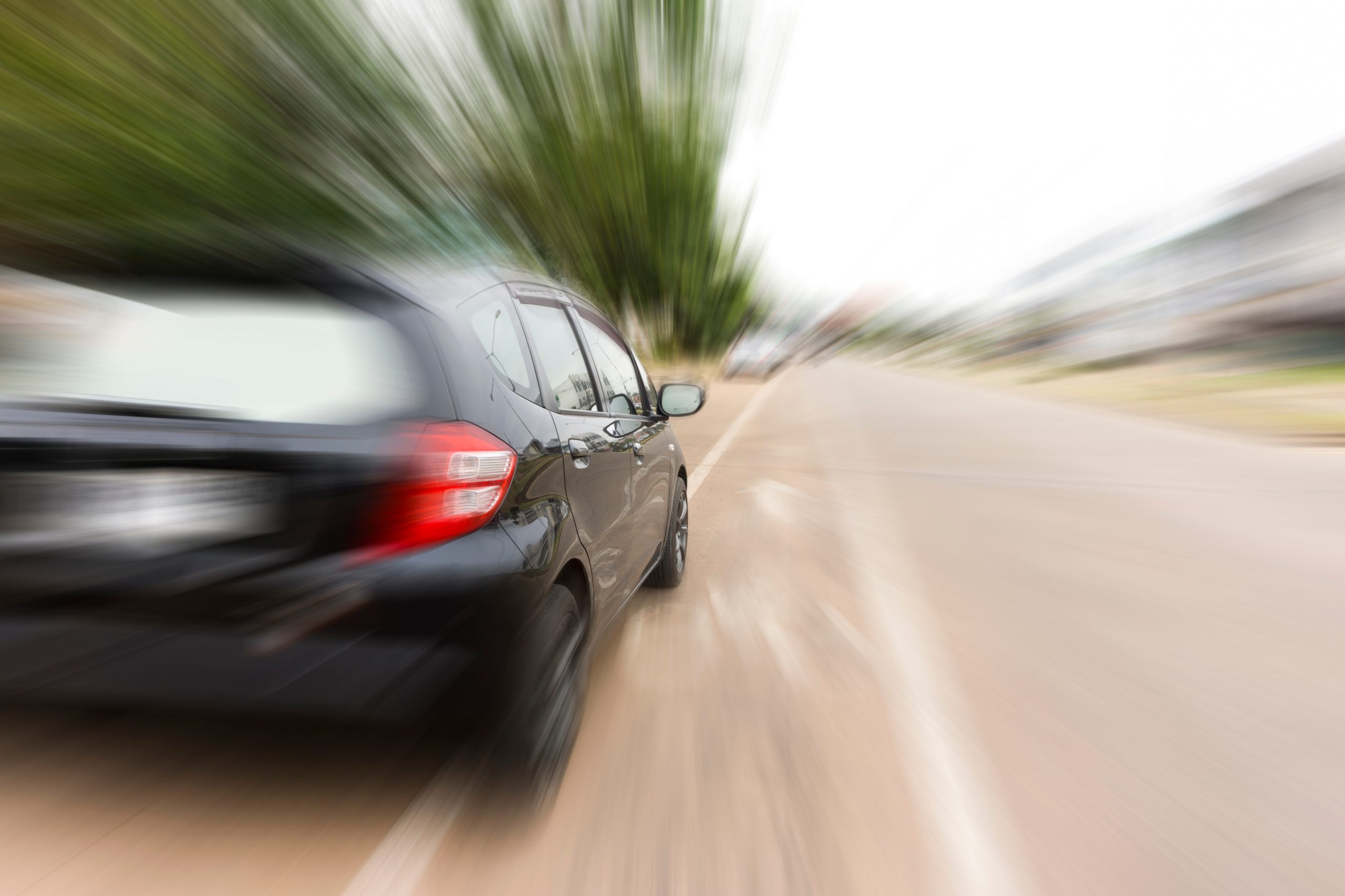 Black car speeding along a road with motion blur.